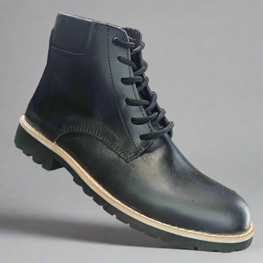 Black leather boot held in a hand with a shoe rack in the background