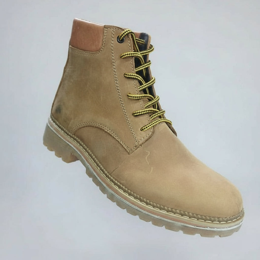 Tan boot held in a hand with a blurred shoe rack in the background