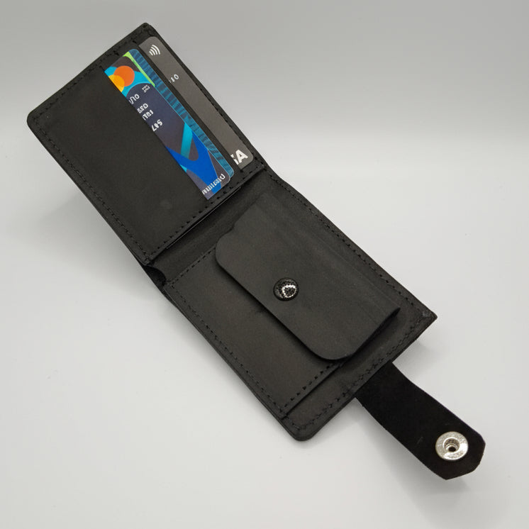 Black leather wallet with card slots held by a hand on a wooden surface.
