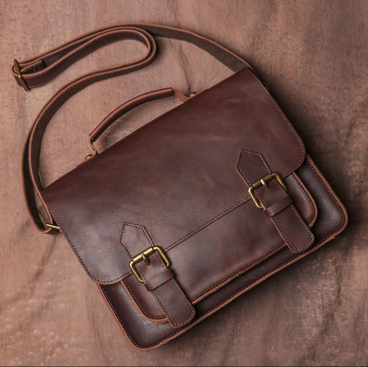 Brown leather satchel bag with gold buckles on a brown background