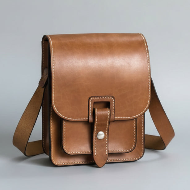 Brown leather satchel bag on a light gray background