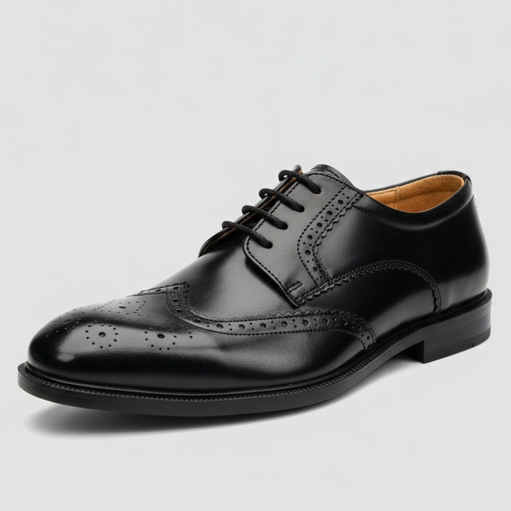 Black leather shoe held in a hand with shelves of shoes in the background