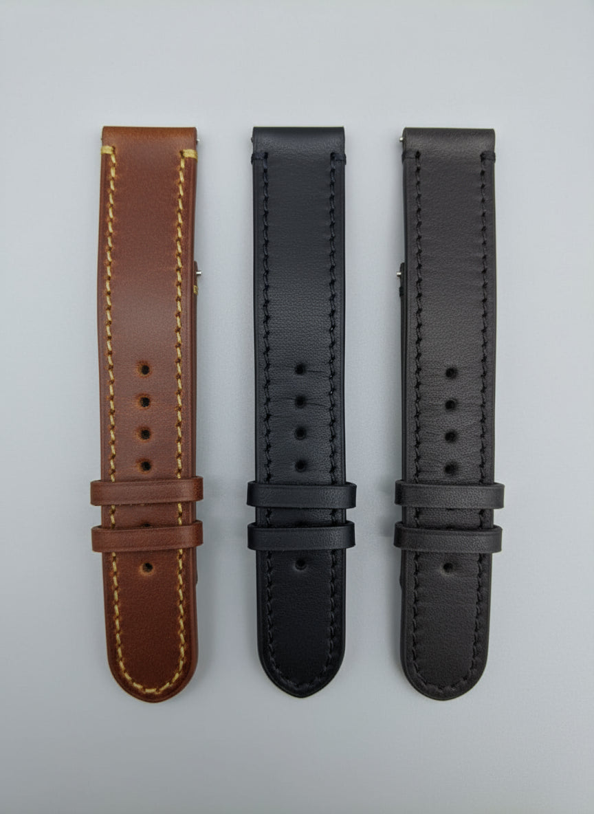 Three leather watch straps on a wooden surface