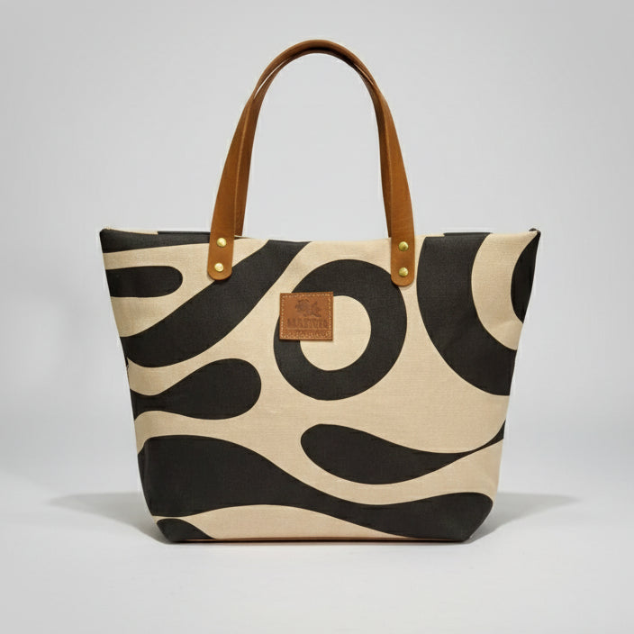 Person reading a book next to a panda-patterned bag on a wooden surface.