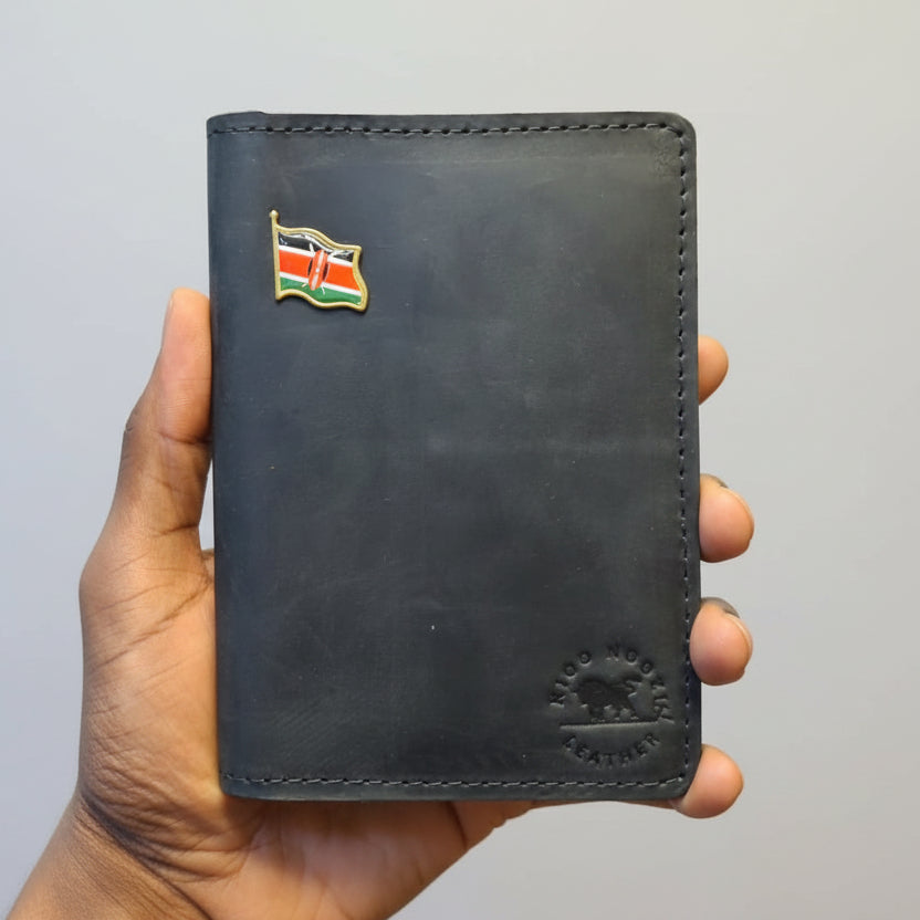 Black leather wallet with a flag pin held by a hand against a gray background