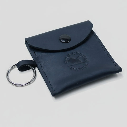 Black leather key pouch with a brand logo on a wooden surface