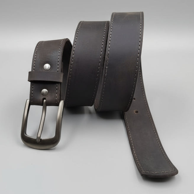 Brown leather belt with a silver buckle on a wooden surface