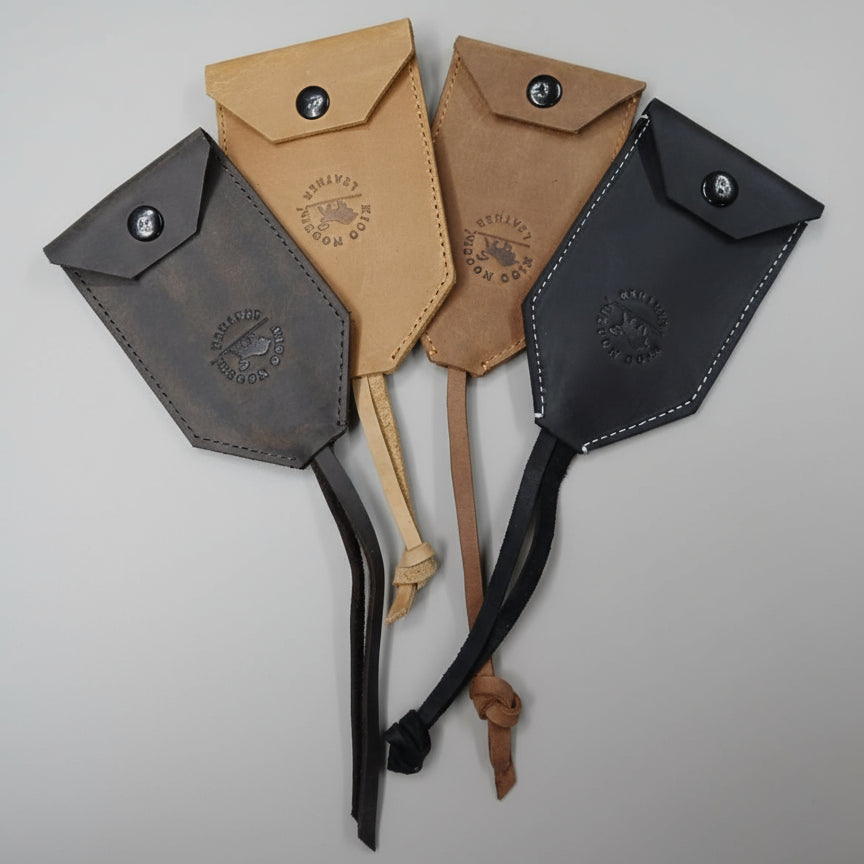 Four leather pouches in different colors on a wooden surface