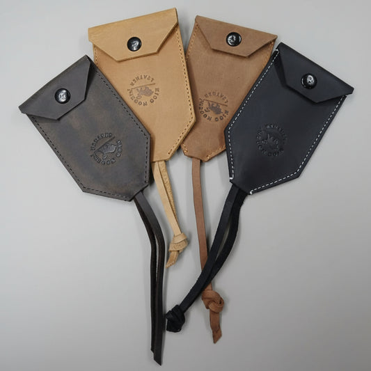 Four leather pouches in different colors on a wooden surface