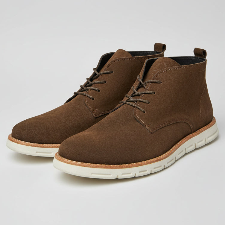 Brown suede chukka boots with white soles on a light gray background
