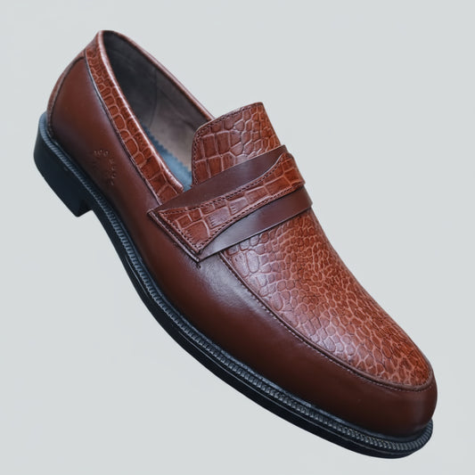 Brown leather loafer held in a hand with a shoe rack in the background