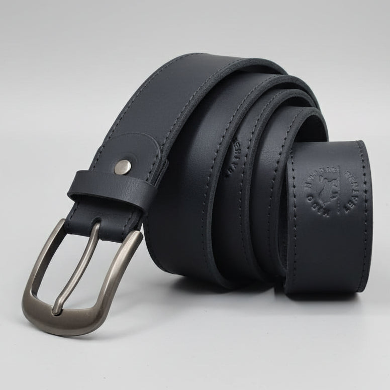 Black leather belt with silver buckle on a wooden surface