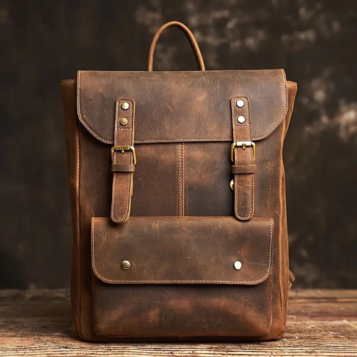 Brown leather backpack on a wooden surface with a dark background