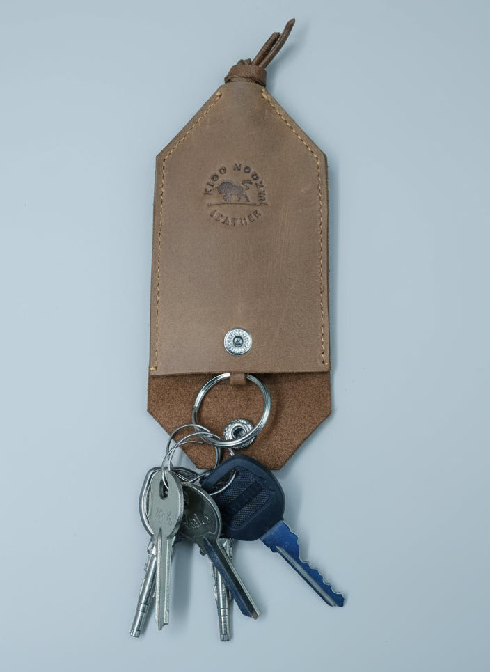 Brown leather keychain with keys on a wooden surface