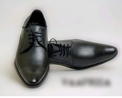 Pair of black dress shoes on a light gray background