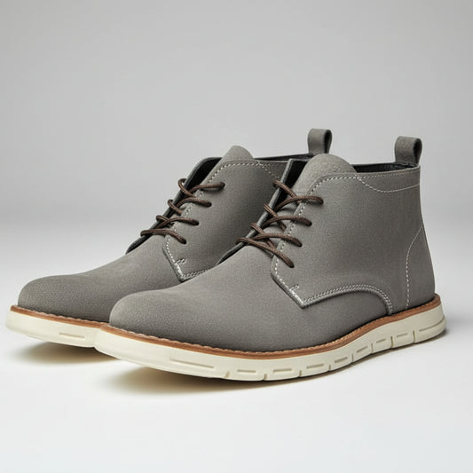Pair of gray leather boots with white soles on a light gray background