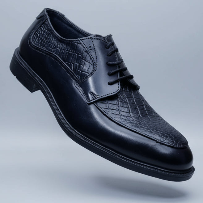 Black leather shoe held in a hand with blurred shoes in the background