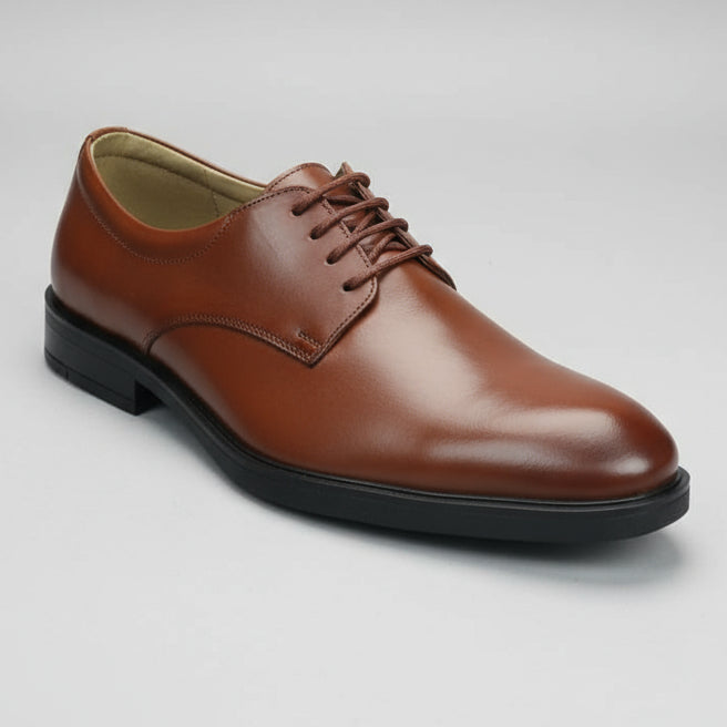 Brown leather shoe held in a hand with a blurred shoe store background