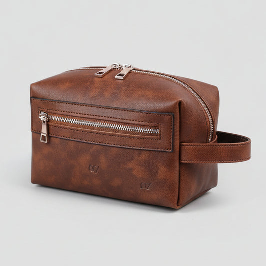 Brown leather toiletry bag with zippers on a light gray background