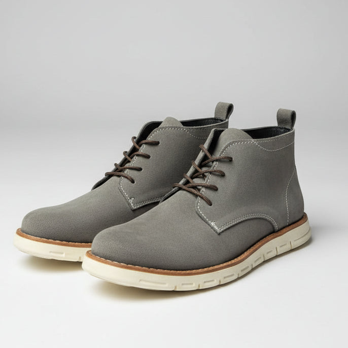 Pair of gray suede boots with white soles on a light gray background