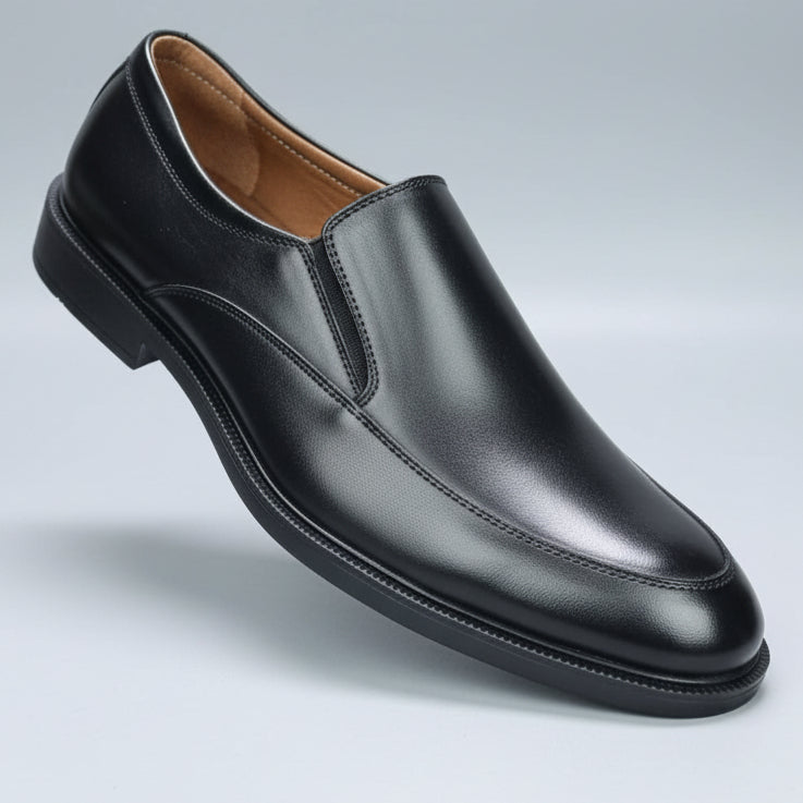 Black leather loafer shoe held in a hand with a blurred background