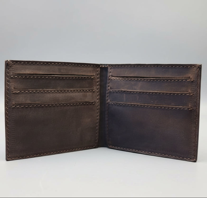 Open brown leather wallet on a wooden surface with a blurred background