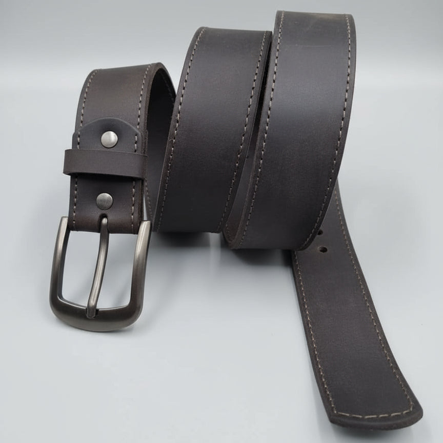 Brown leather belt with a silver buckle on a wooden surface