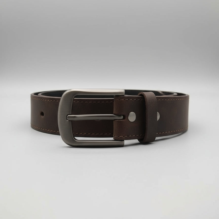 Brown leather belt with metal buckle on a wooden surface
