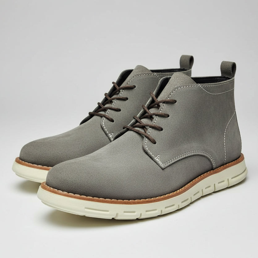 Gray suede shoe with white sole held in a shoe store