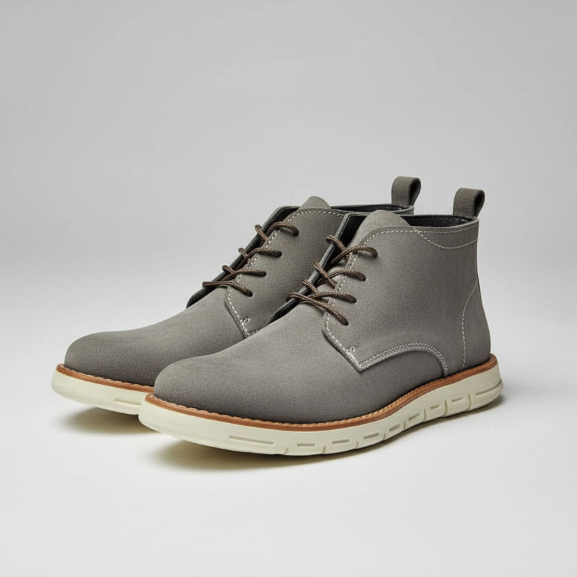 Gray suede boots held up in a shoe store with wooden shelves in the background