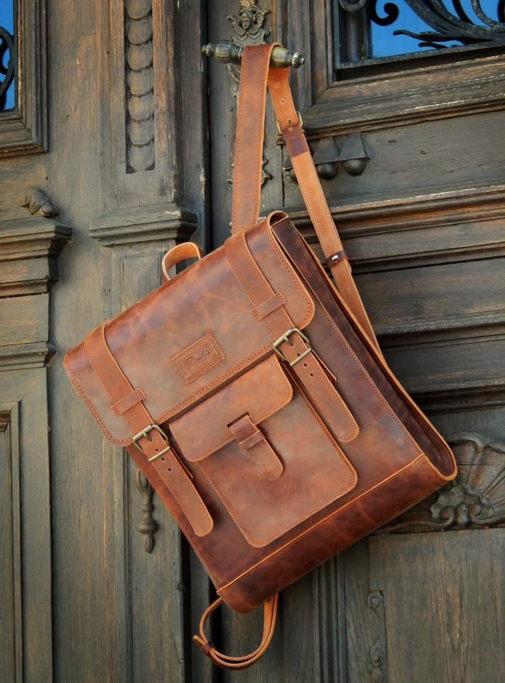 Brown leather satchel bag hanging on a wooden door