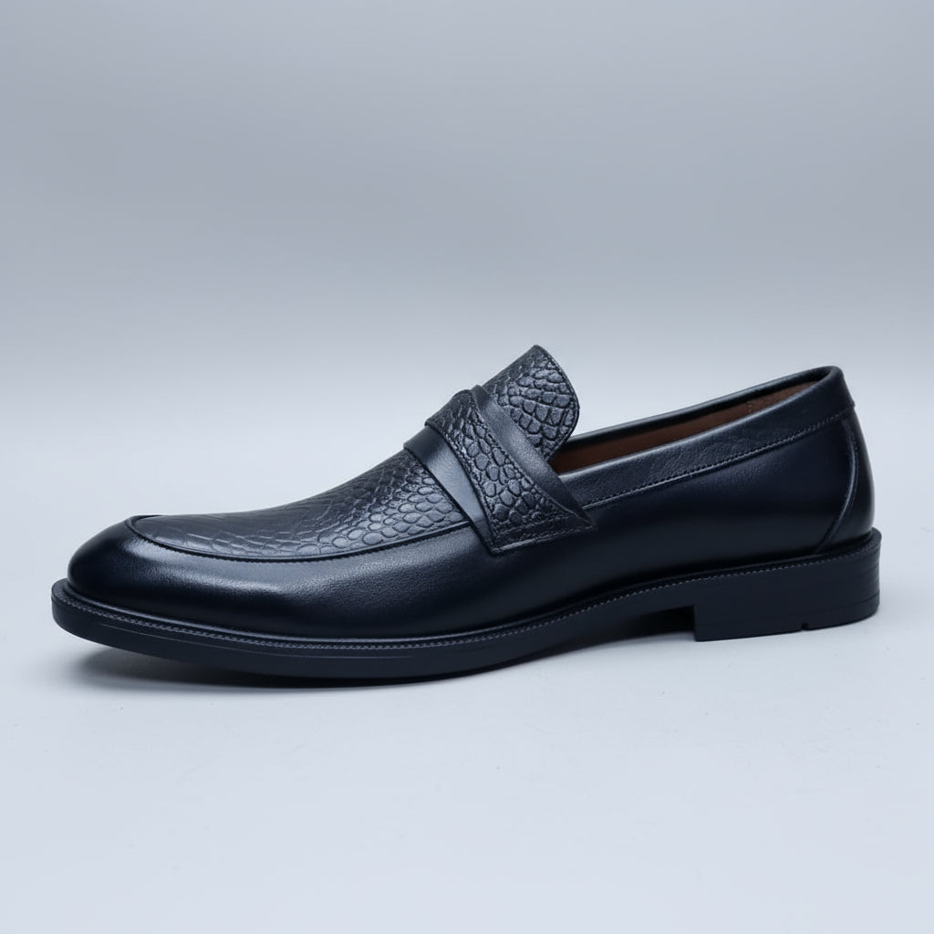 Black leather loafer held in a hand with shoes in the background