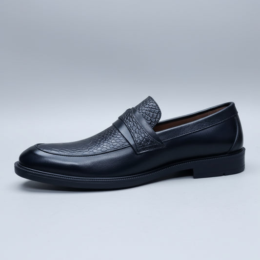 Black leather loafer held in a hand with shoes in the background