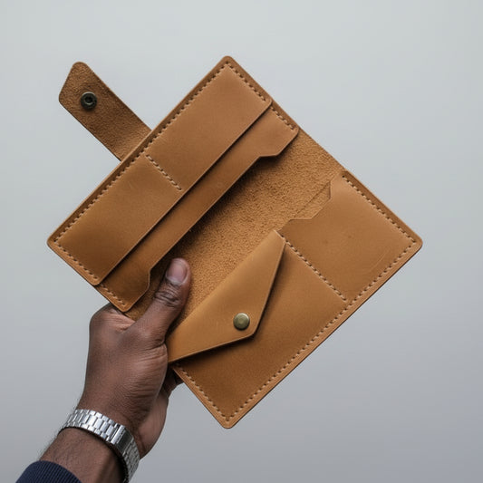Brown leather wallet held by a hand against a gray background
