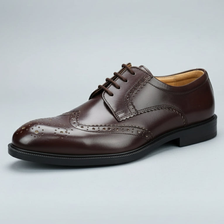 Brown leather shoe held in front of a shoe rack with various shoes.