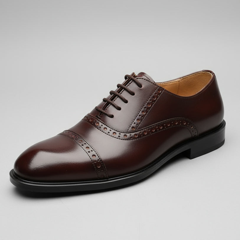 Brown leather shoe held in a hand with a shoe rack in the background