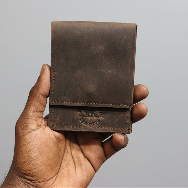 Brown leather wallet held in a hand with a blurred background