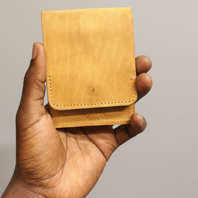 Hand holding a brown leather wallet against a reflective surface