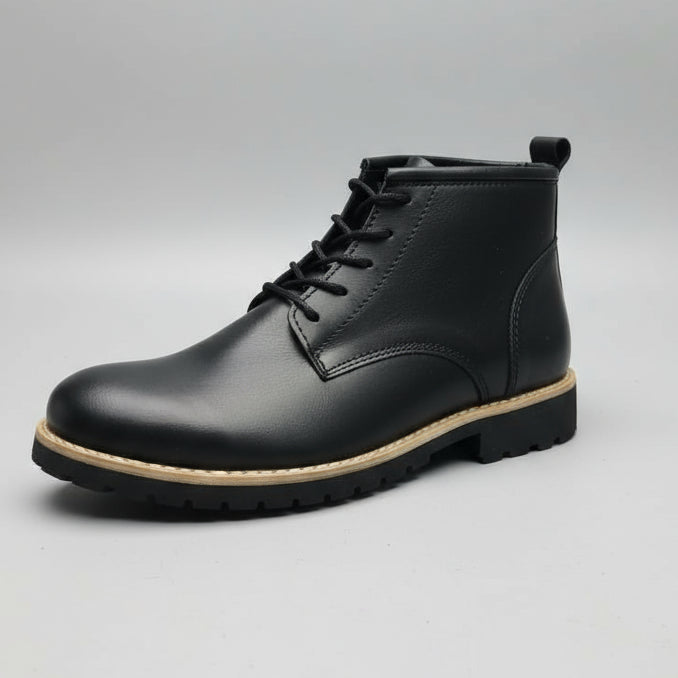 Black leather boot held in a hand with a blurred shoe store background
