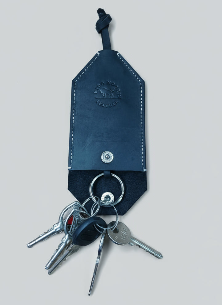 Black leather key holder with keys on a wooden surface